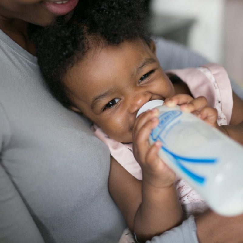 baby holding bottle and drinking