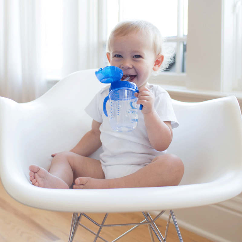 toddler sitting in chair drinking from straw cup