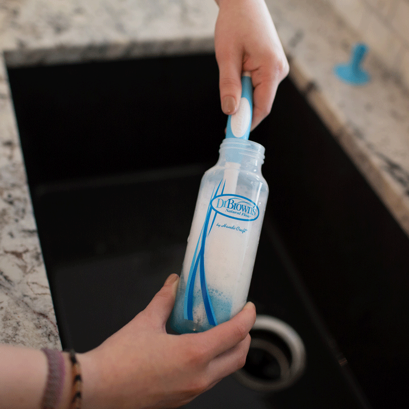 baby bottle being cleaned with bottle brush