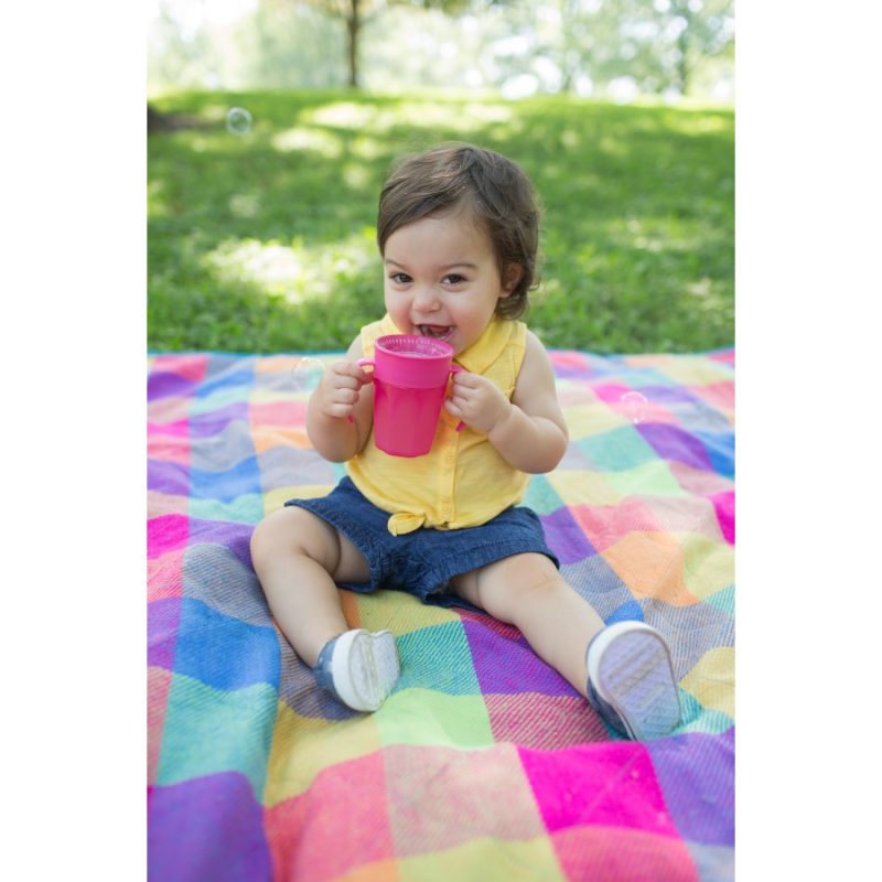 baby sitting on picnic blanket and bring from cup
