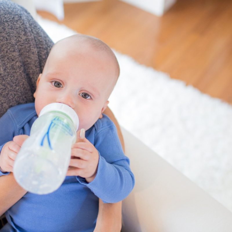 women holding and feeding baby with baby bottle