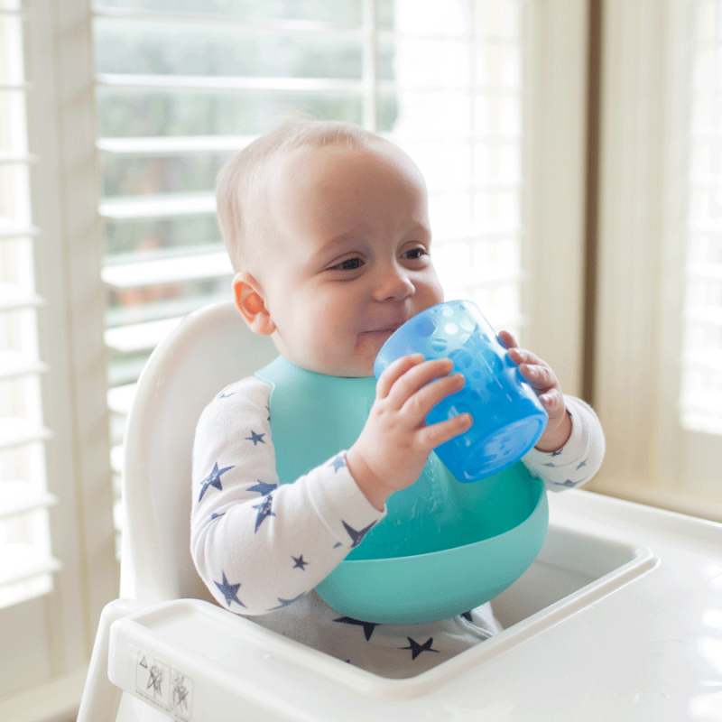 baby in highchair drinking from tumbler